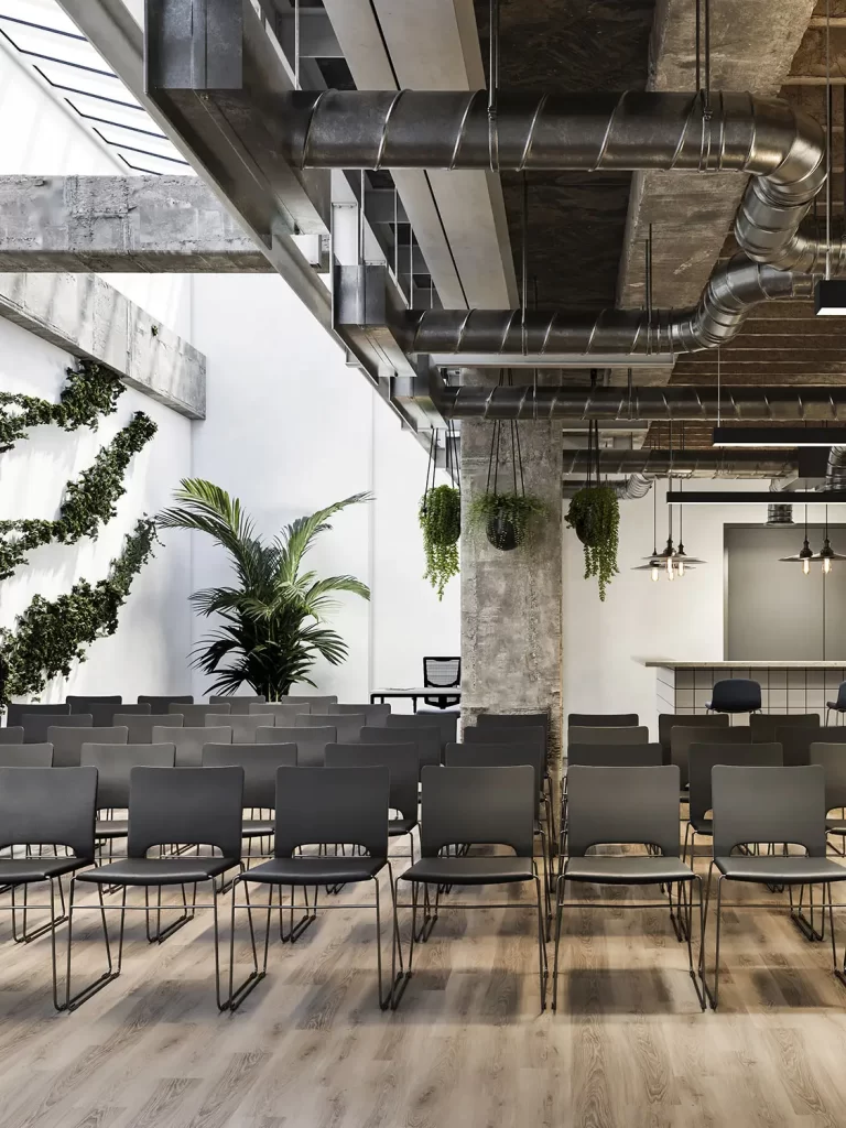 3D render of a modern office event space with rows of chairs, industrial design elements, and hanging plants.