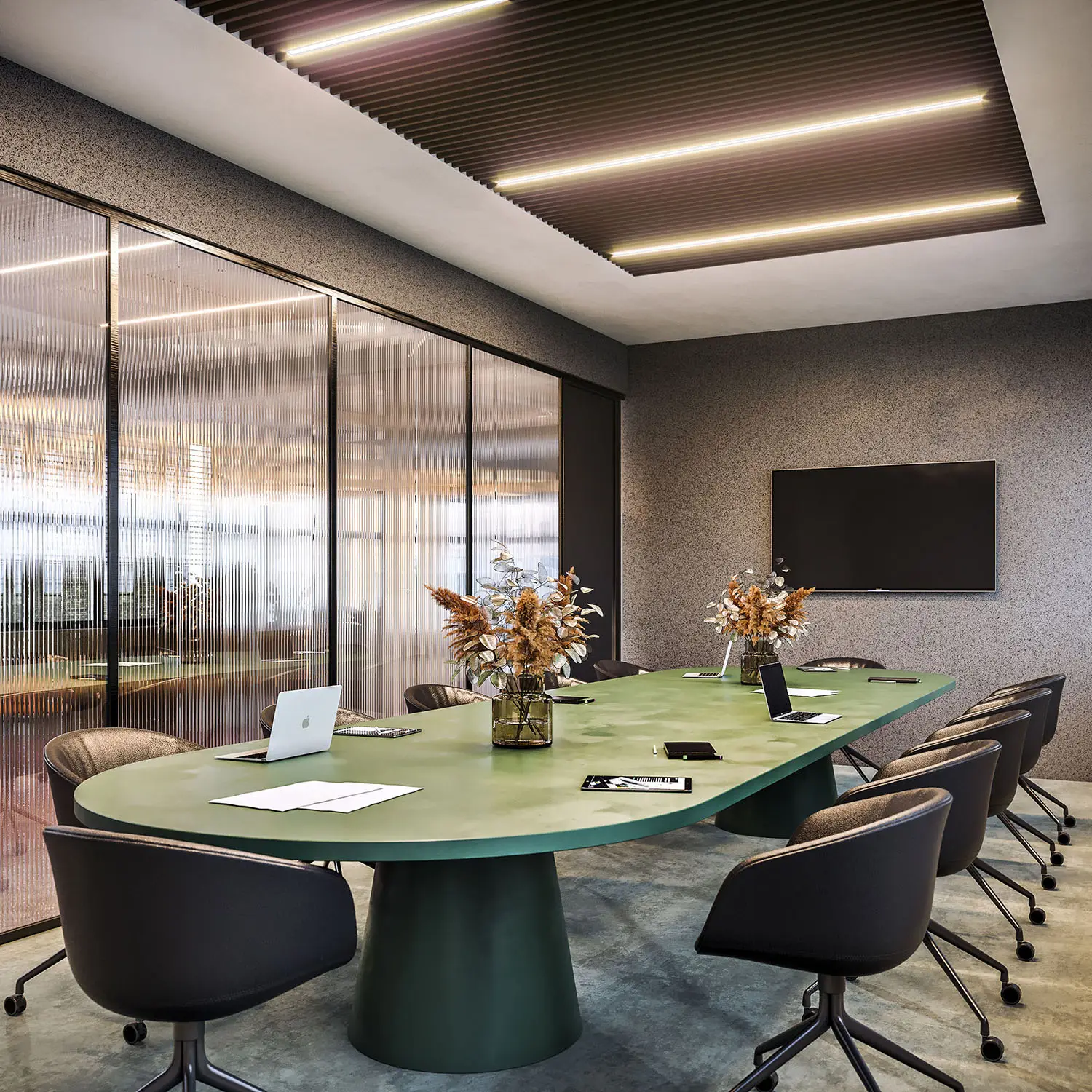 Modern conference room with a large green table, stylish chairs, and minimalist design.