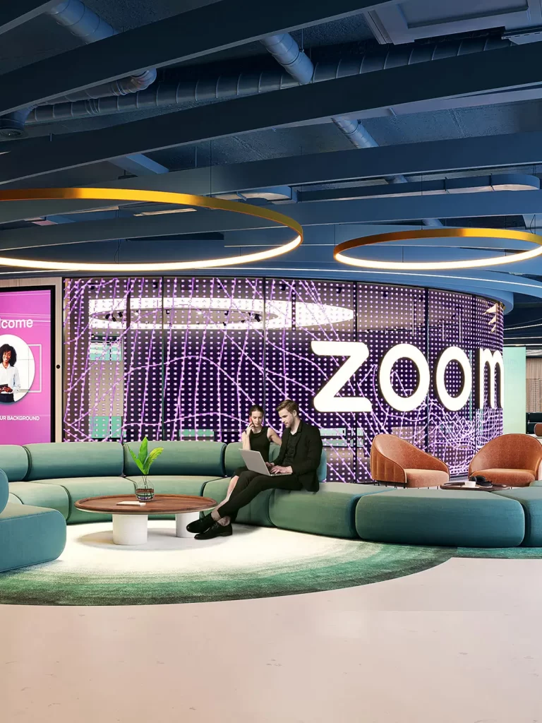 3D render of a modern Zoom lounge area with circular seating, digital wall displays, and two people working on a laptop, by 100CGI Studio.